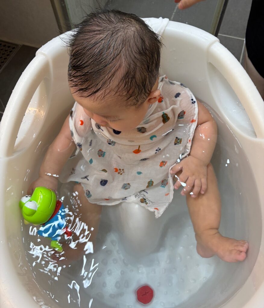 욕조 물에 띄운 수영하는 크롱을 바라보며 집중하는 6개월 아기