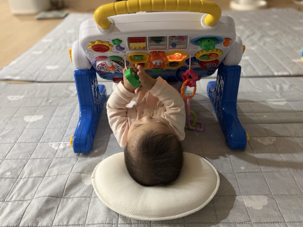 코니스 에듀테이블 아래에서 손으로 장난감을 만지며 노는 아기