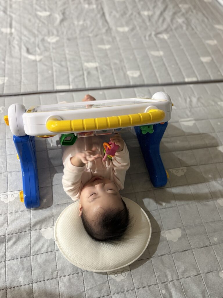 누워서도 코니스 에듀테이블 장난감에 손을 뻗는 아기 모습